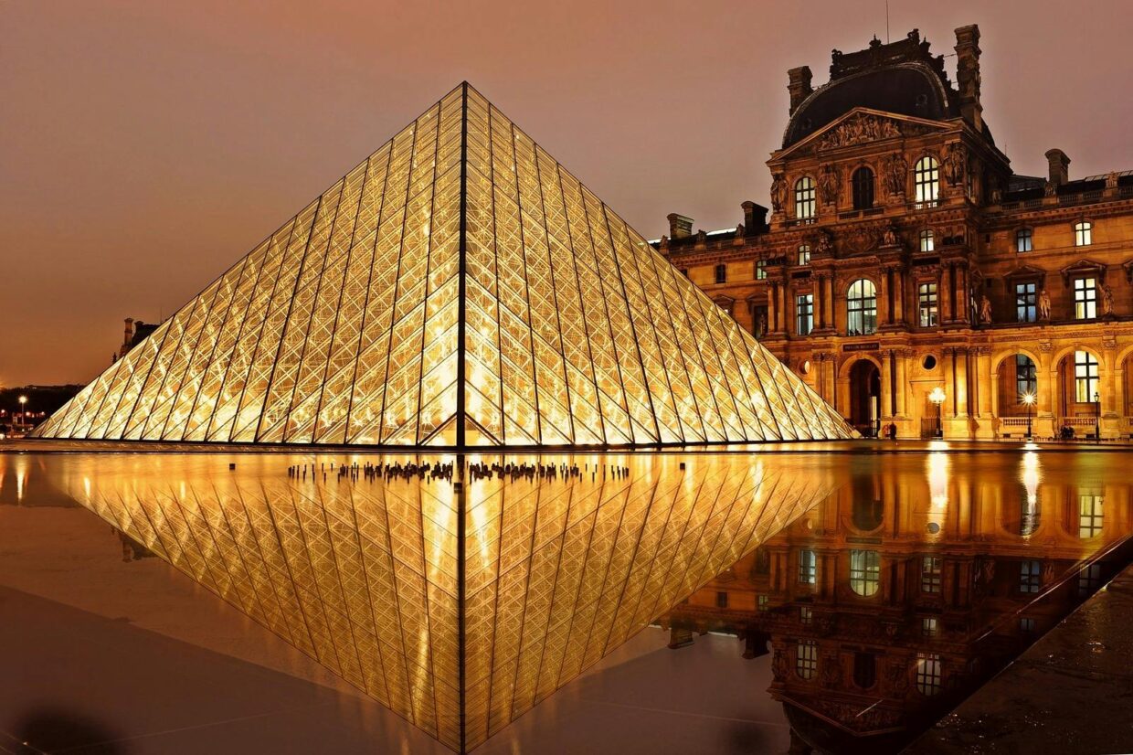 Pirâmide de vidro do Louvre iluminada ao entardecer, em Paris