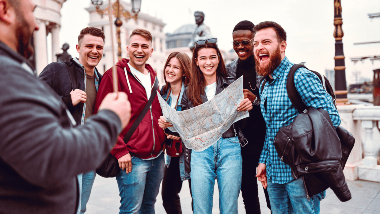 Grupo de amigos sorrindo e olhando um mapa durante uma viagem em grupo