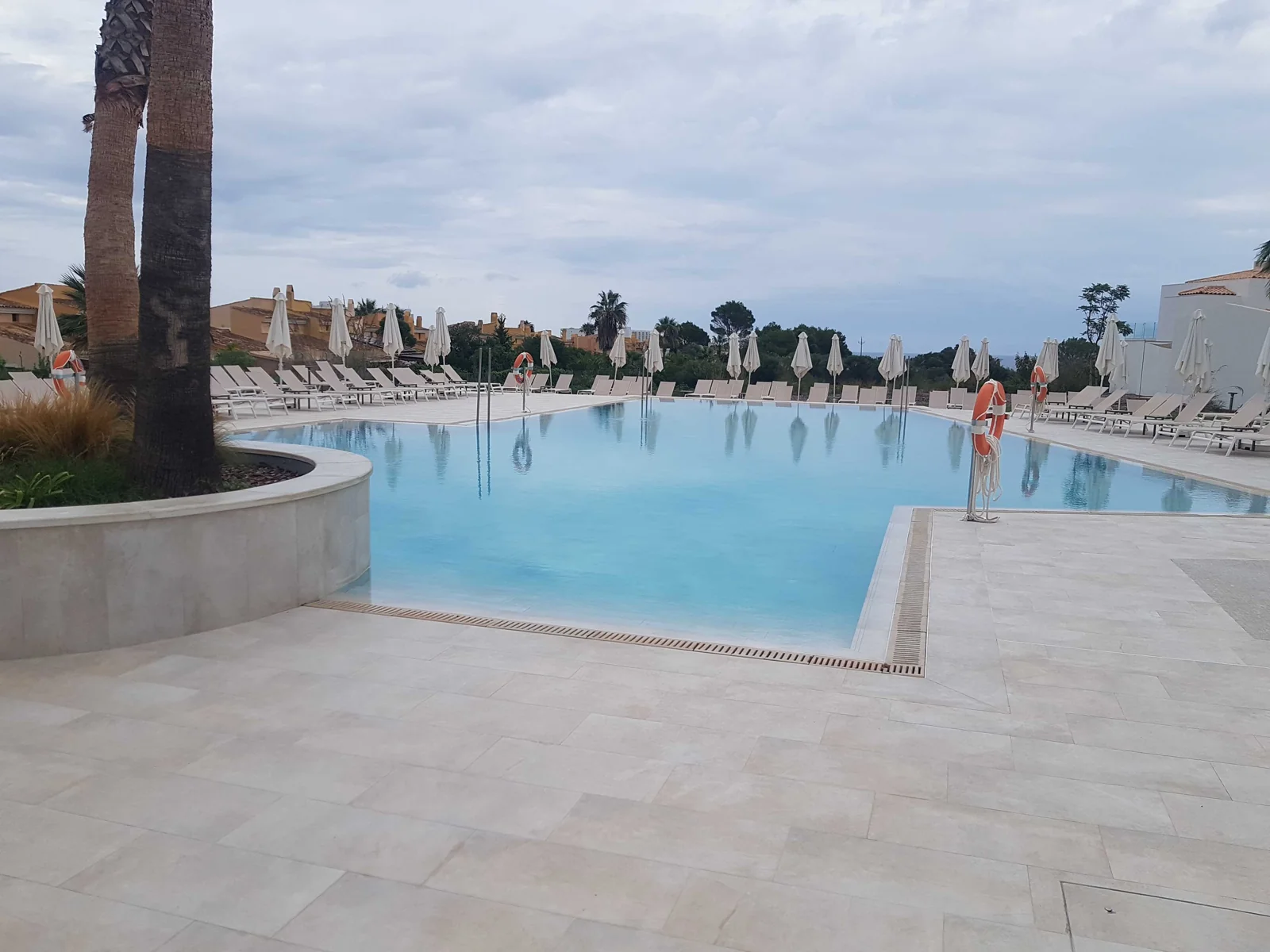 Piscina do Iberostar Cala Domingos, em Mallorca, cercada por espreguiçadeiras e guarda-sóis brancos.