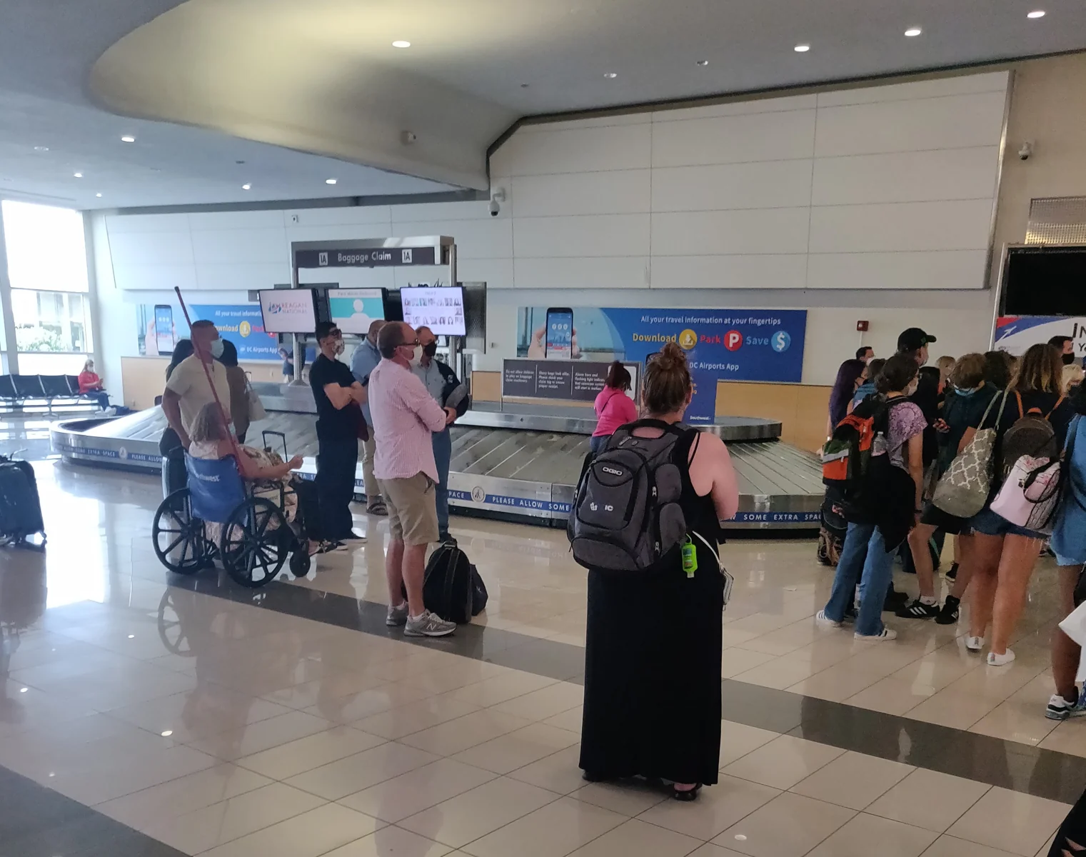 Esteira de retirada de bagagens no Aeroporto Ronald Reagan Washington National, com passageiros ao redor.