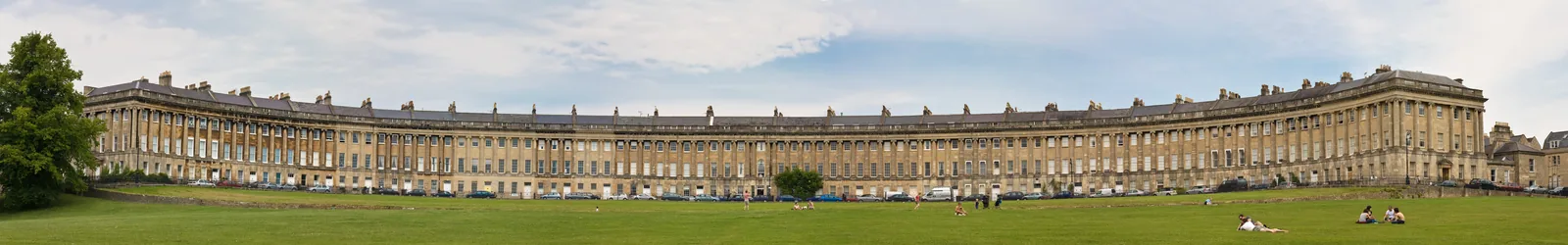 Vista panorâmica das fachadas curvas do Royal Crescent, em Bath, diante de um gramado.