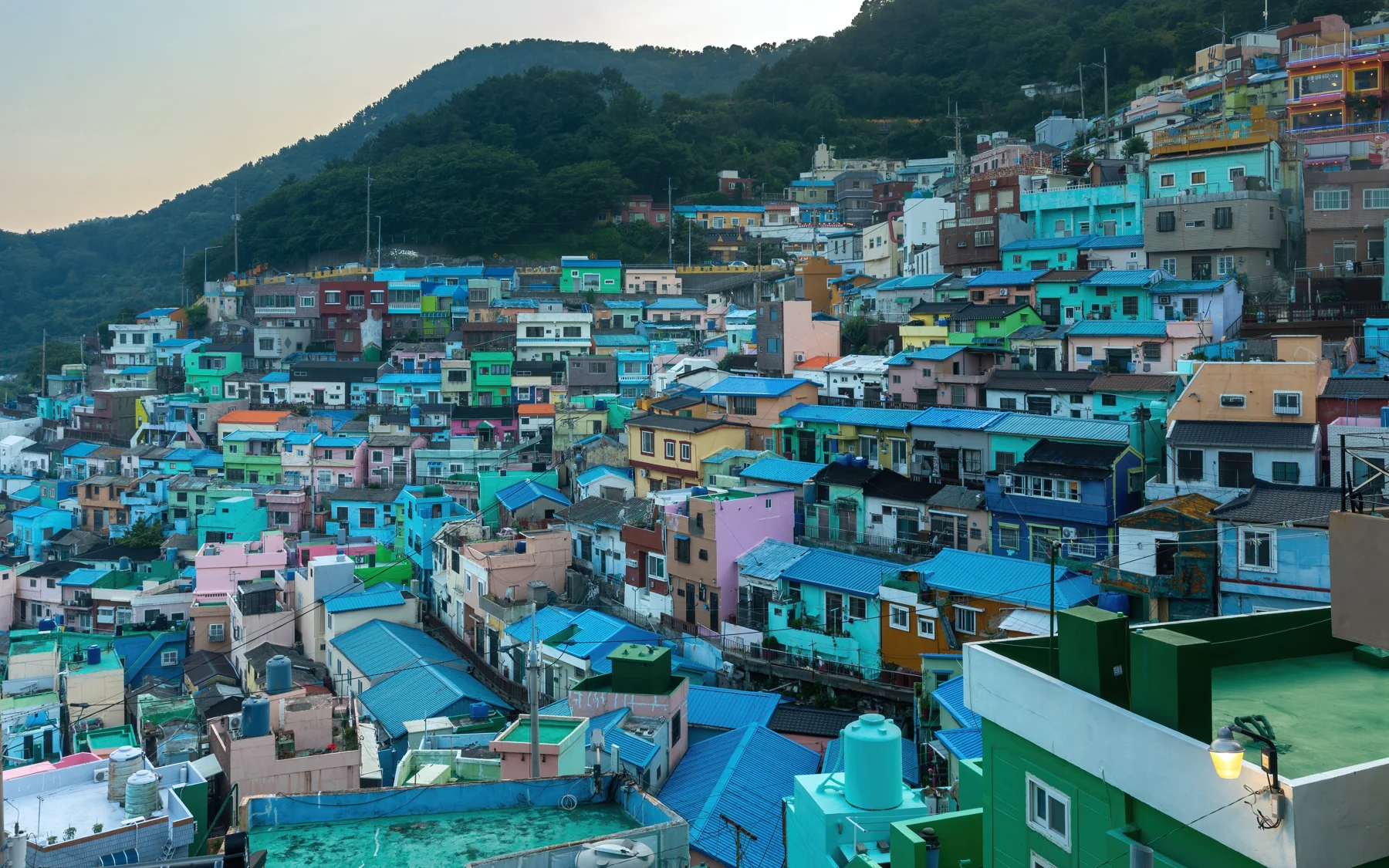 Casas coloridas de Gamcheon distribuídas pelas encostas de Busan ao pôr do sol.