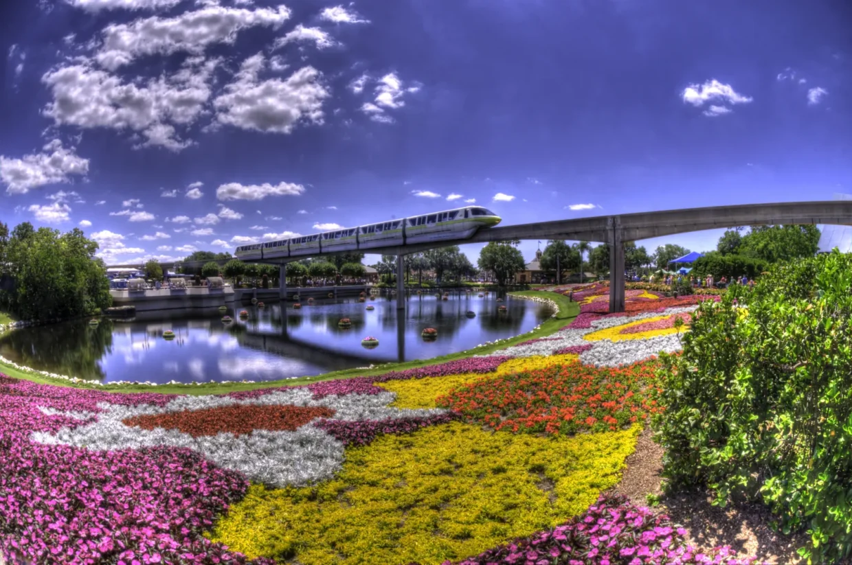 Canteiros floridos e monorail sobre um lago no EPCOT durante uma edição do Flower & Garden Festival.