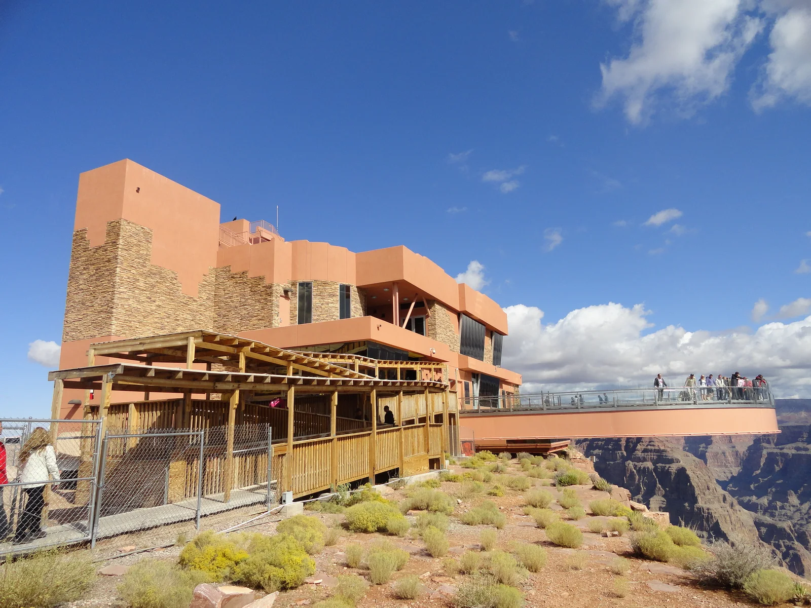 Vista lateral do Grand Canyon Skywalk, com visitantes na passarela e o cânion abaixo.