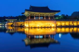 Pavilhão iluminado de Donggung refletido nas águas do lago Wolji ao anoitecer, em Gyeongju.
