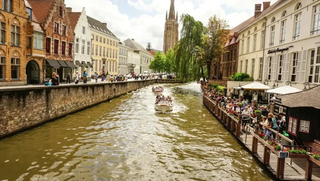Barco de passeio em canal de Bruges, na Bélgica, com casas históricas às margens