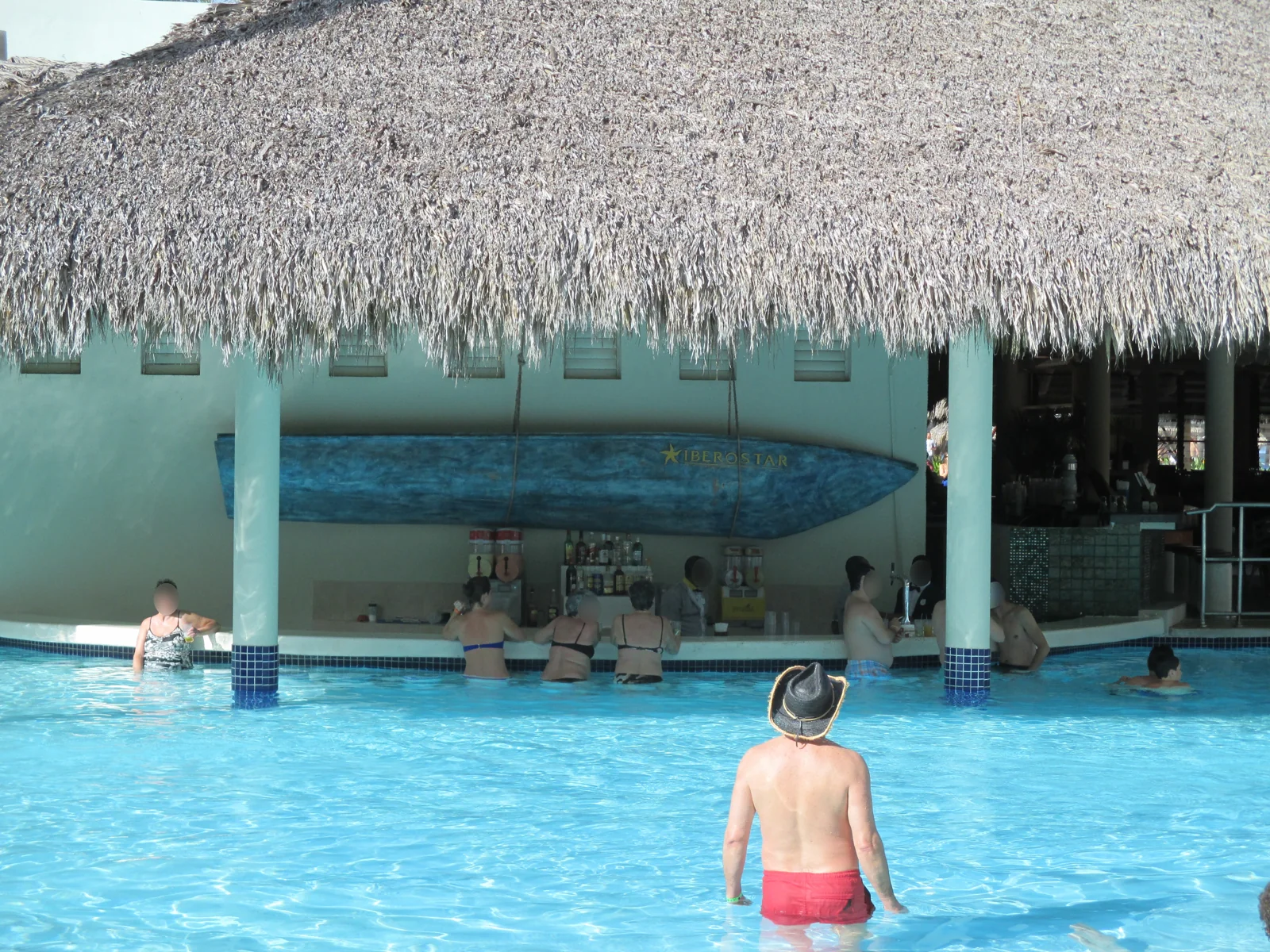 Bar dentro da piscina de um resort Iberostar em Bávaro, com cobertura de palha e hóspedes na água.