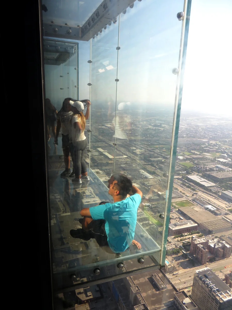 Visitantes no balcão de vidro The Ledge, no Skydeck Chicago, com a cidade visível abaixo.
