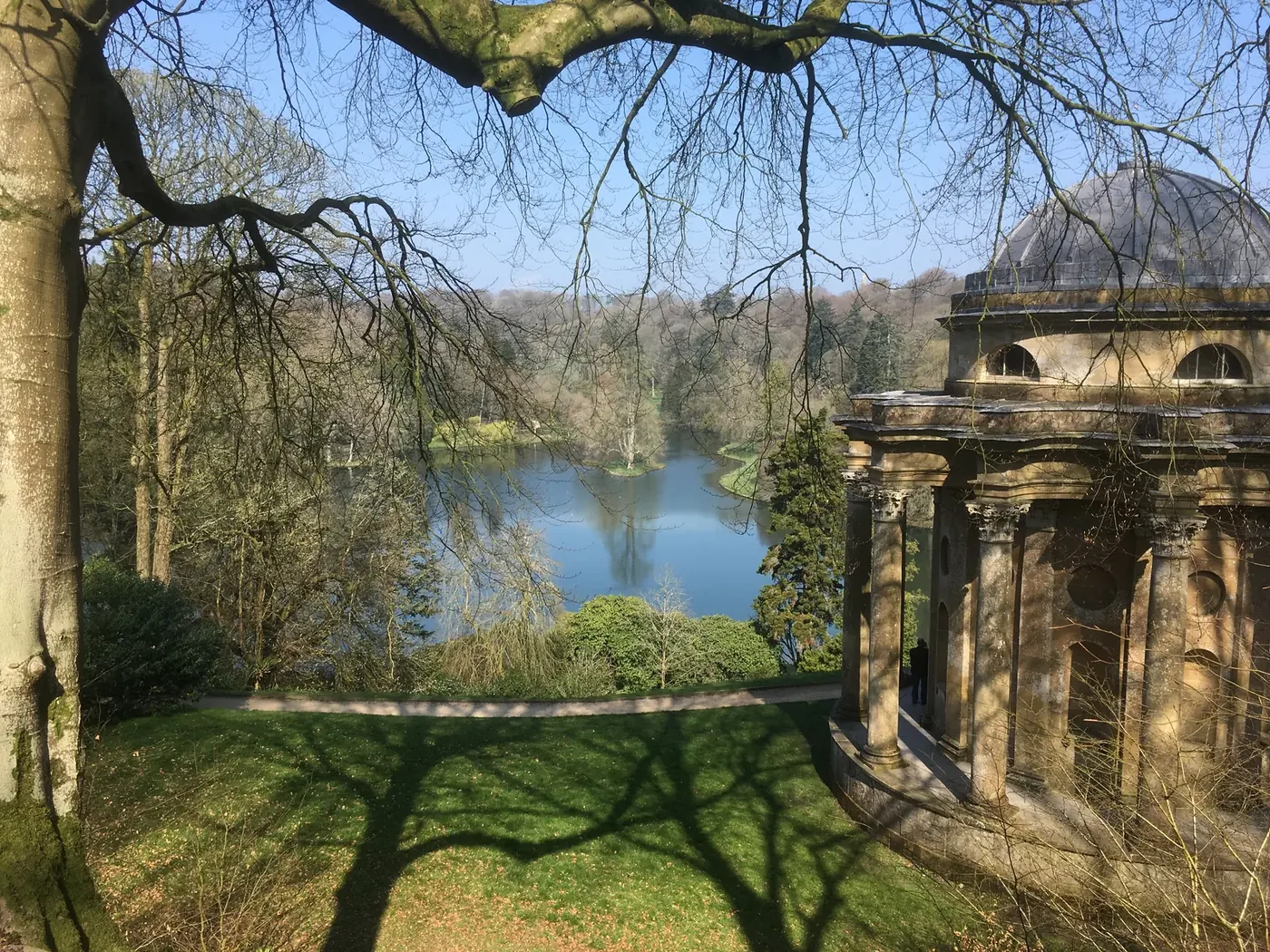 Templo de Apolo entre árvores nos jardins de Stourhead, com o lago ao fundo.