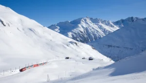 Glacier Express vermelho atravessando uma paisagem de montanhas cobertas de neve perto do passo de Oberalp.