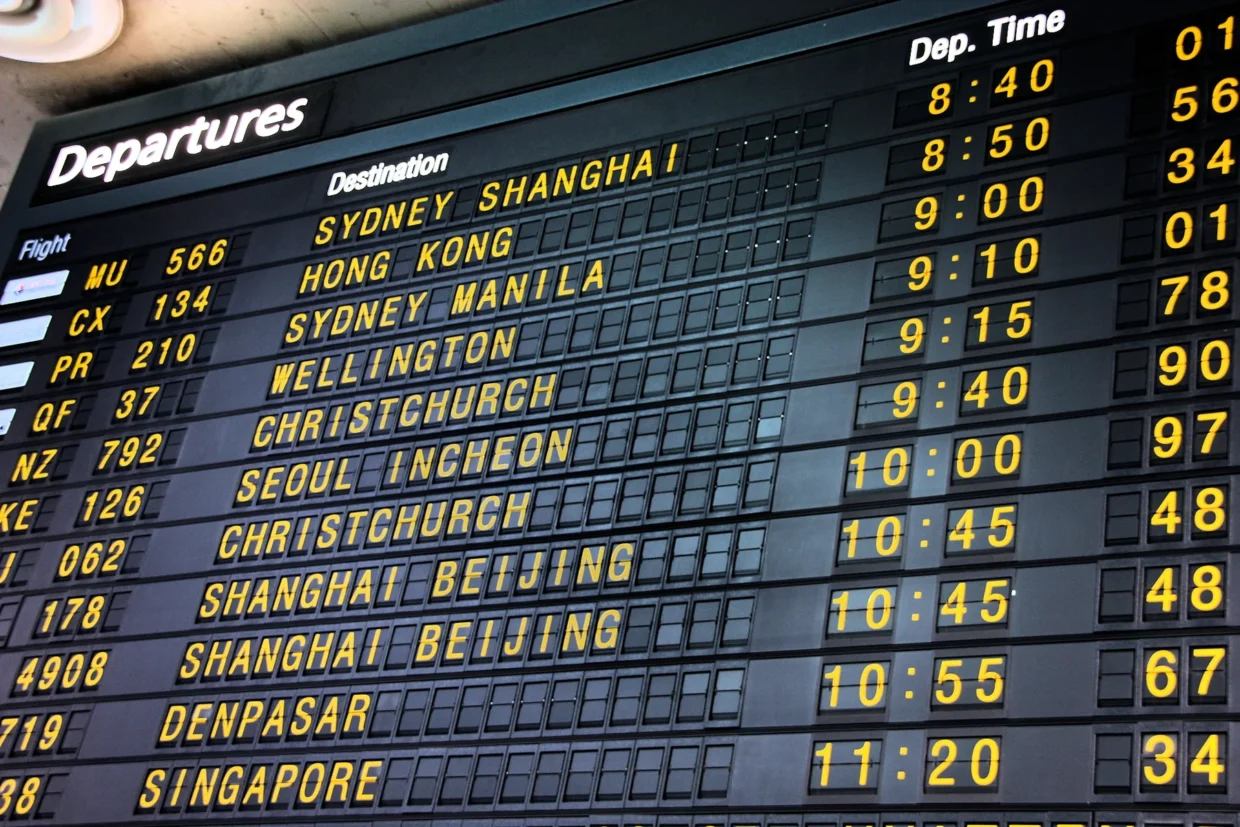 Painel de partidas do Aeroporto de Melbourne com destinos, números de voos e horários em letras amarelas.